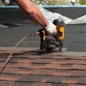 roofers installing a new roof on residential home. weatherlock material and brown asphalt roofing shingles